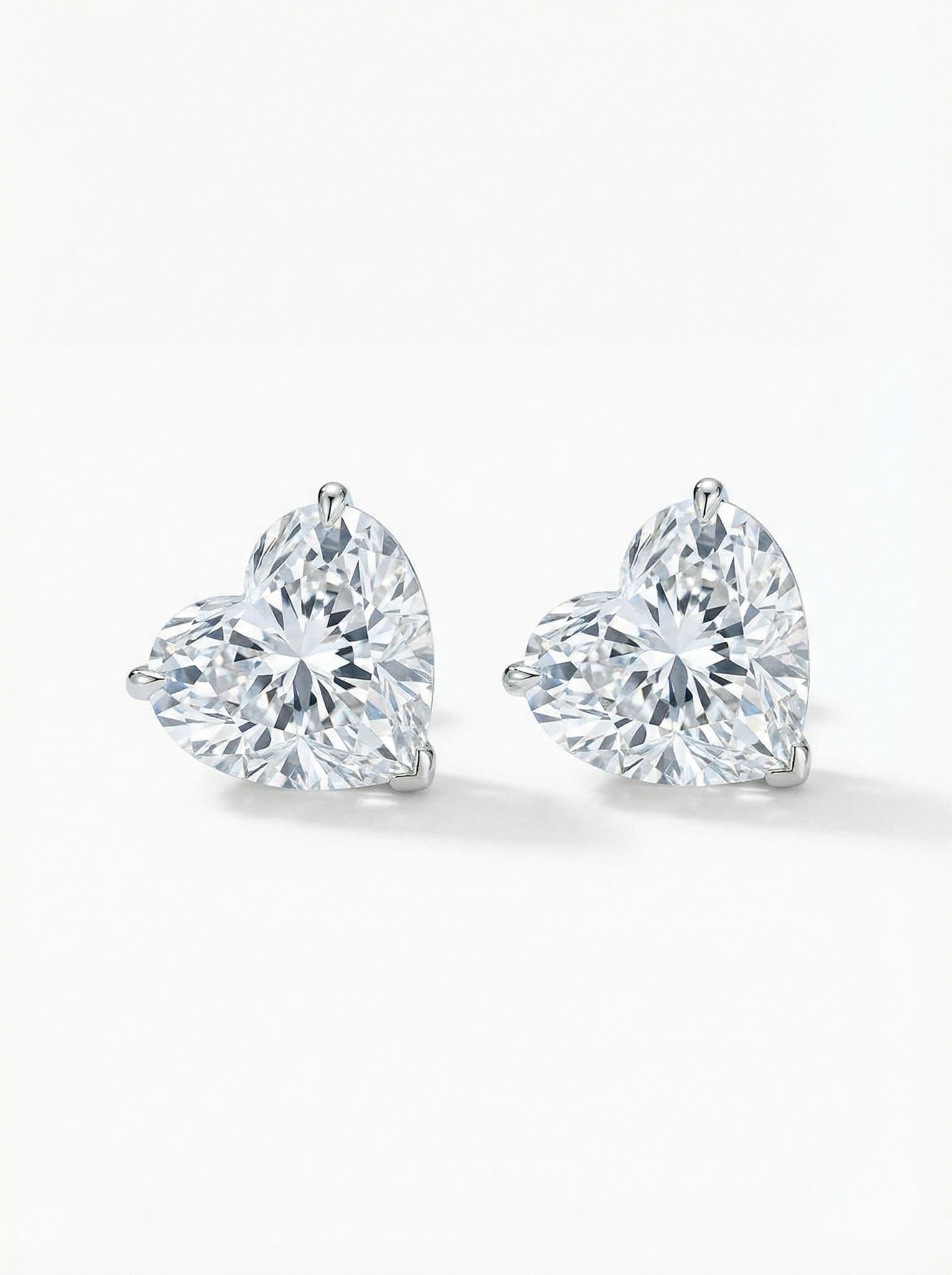 Pair of heart-shaped diamond stud earrings on a white background