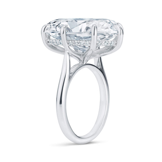 Platinum ring with very large oval diamond, from the side, showing a halo of small diamonds behind the large one.